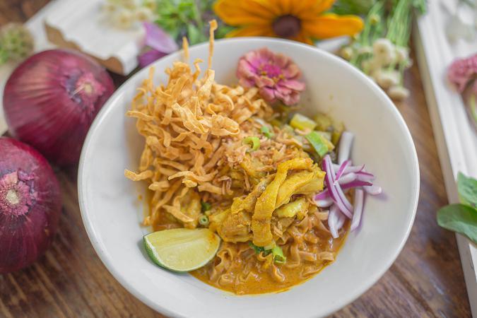 Khao Soi · Marinated beef or chicken with Northern-style red curry and egg noodles garnished with shallots, limes, and pickled vegetables. Mild spicy