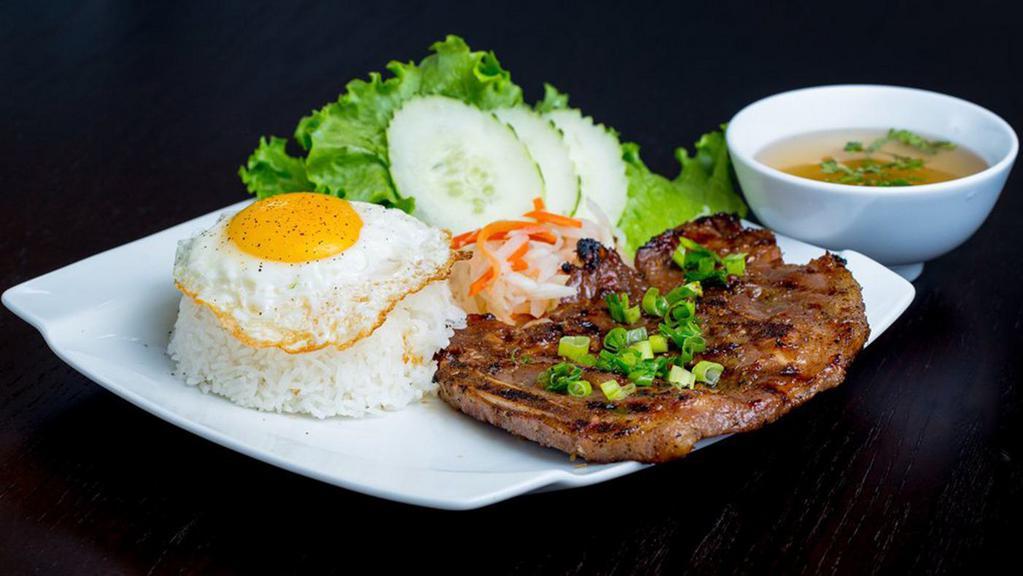 8. Lemongrass Pork Chop · Grilled pork chop and fried egg served with rice, lettuce, cucumber, veggie pickles and fish sauce on the side.