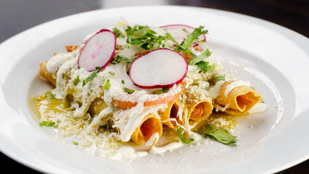 Taquitos de Pollo · Hand rolled fried tacos stuffed with chicken, topped with cabbage slaw, cheese, sour cream. Garnished with cilantro, onions and tomatoes. Dressed in salsa verde.