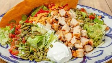 GRILLED CHICKEN TACO SALAD · Homemade tostada taco shell filled with romaine lettuce, refried beans, pico de gallo, cotija cheese and jack cheese. Topped with grilled chicken, roasted pepitas, sour cream, guacamole and your choice of dressing.