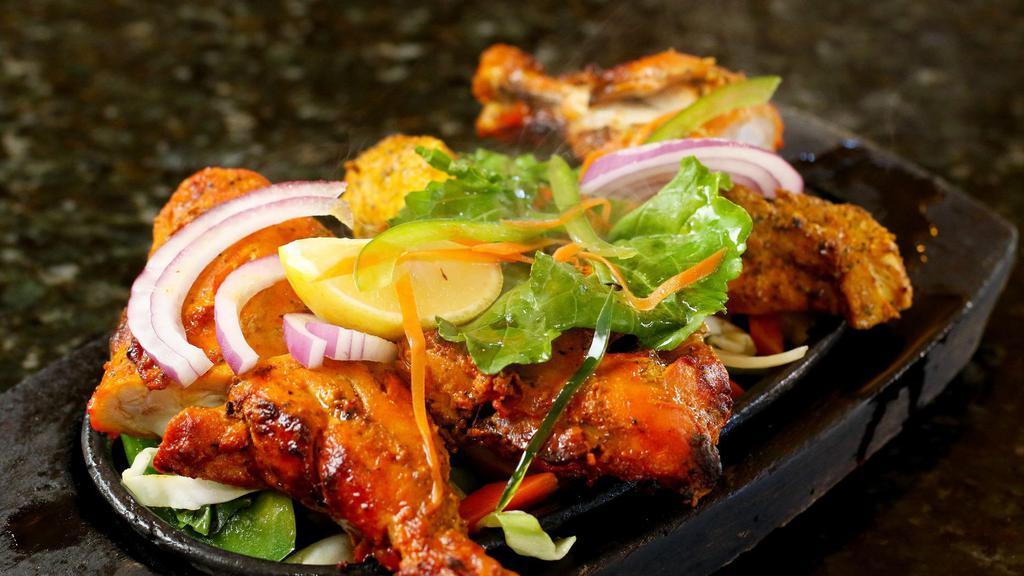 Chicken Tandoori · Chicken with bones marinated in yogurt and spices, broiled in the tandoor clay oven and served in sizzling platter with sautéed onions, bell peppers, cabbage and carrots.