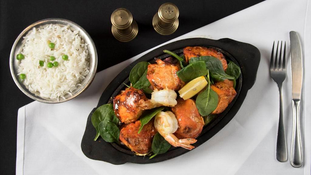 Chicken Tikka Tandoori · Boneless chicken breast marinated with herbs and spices with yogurt then baked in tandoor oven and served in sizzling platter with sautéed onions, bell peppers, cabbage and carrots.