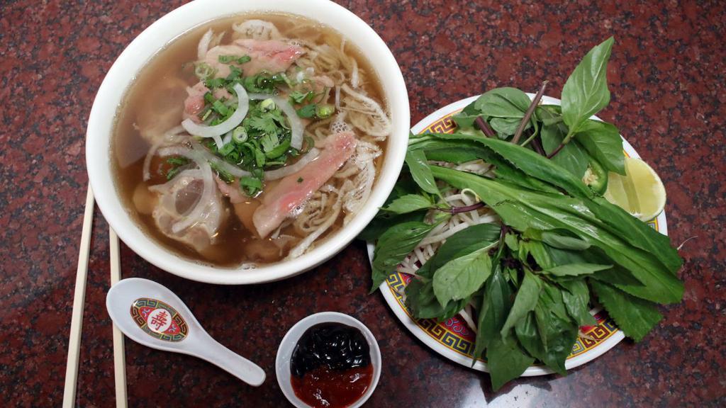1. Phở Dặc Biệt Xe Lửa (Tái, Nam, Gân, Sách) · Large combo rice noodle soup with rare beef, flank tendon and tripe.