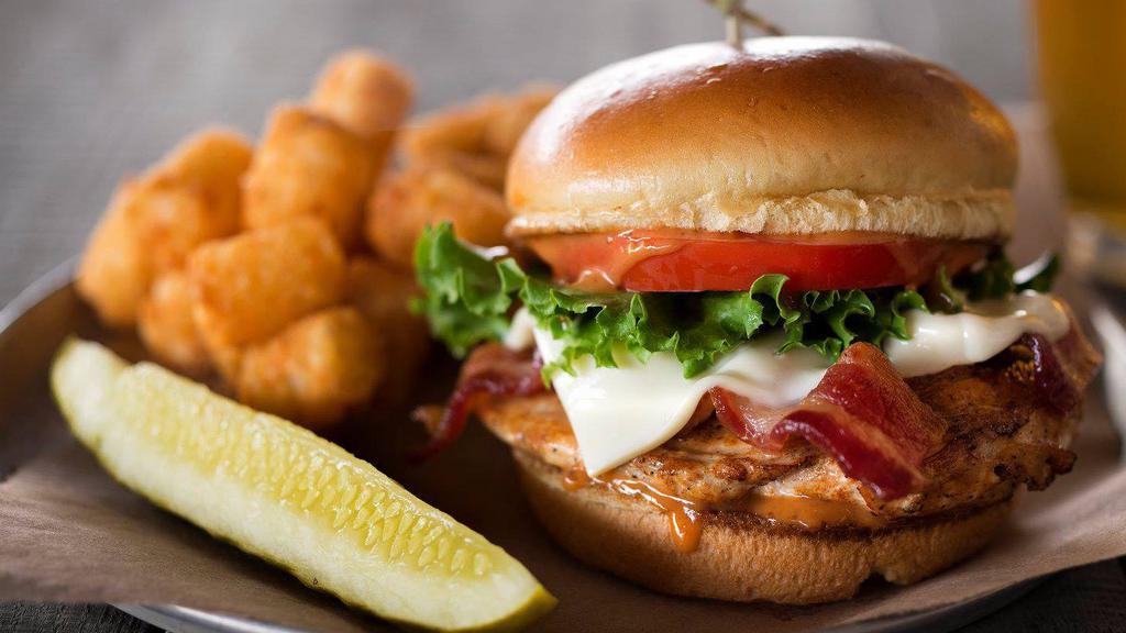 Chipotle Chicken Sandwich · Grilled beer-brined chicken breast smothered in bacon, swiss cheese, and chipotle sauce, served on a lightly toasted brioche bun with lettuce and tomato.