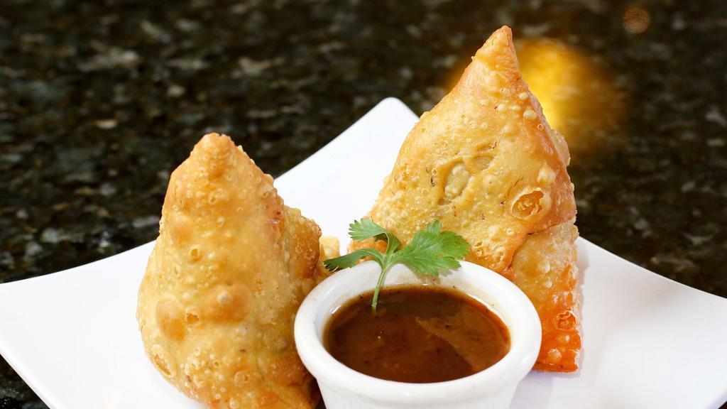 Samosa (2 Pieces) · Vegan. Fried triangular dough stuffed with potatoes, peppers, and cilantro seeds. Served with tamarind chutney.
