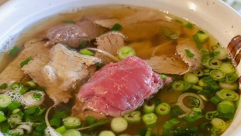 Pho bo, Vietnamese beef soup · Hot soup of grass fed beef bone broth, served with thin rice noodles, sliced braised beef, and topped with shaved rare sirloin,  scallions, cilantro, and rau ram.
