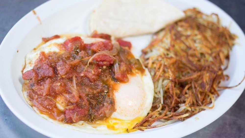 Huevos Rancheros · Eggs covered with fresh salsa on a tortilla topped with vegetarian refried beans and cheese with potatoes or red beans.