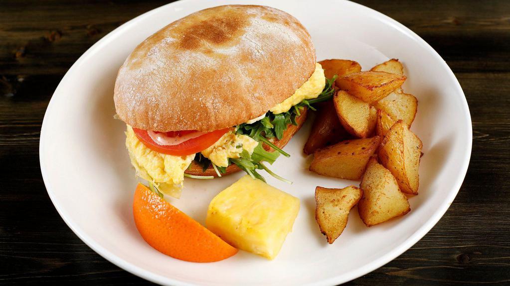 Breakfast Sandwich · Toasted bun, two feta scrambled eggs, arugula, tomatoes, house sauce & crispy potatoes (Nut-Free)