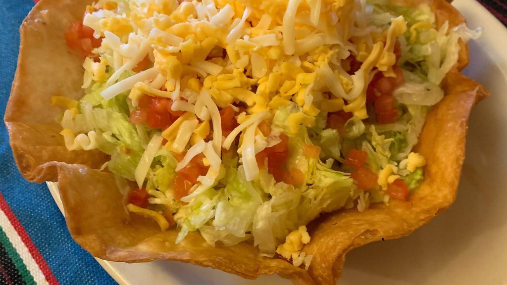 Tijuana Taco Salad · Your choice of beef, picadillo or chicken in a bowl shape our tortilla shell with beans, lettuce, cheese, and then topped with tomato.