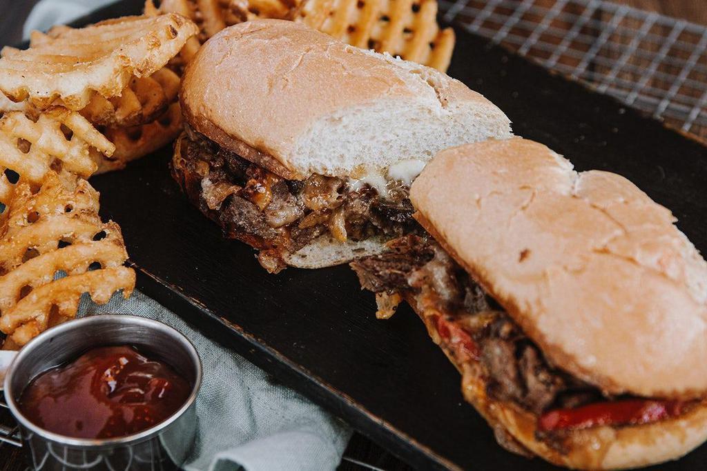 Philly Cheesesteak · Shaved sirloin, american + pepper jack cheese, grilled onions and peppers.