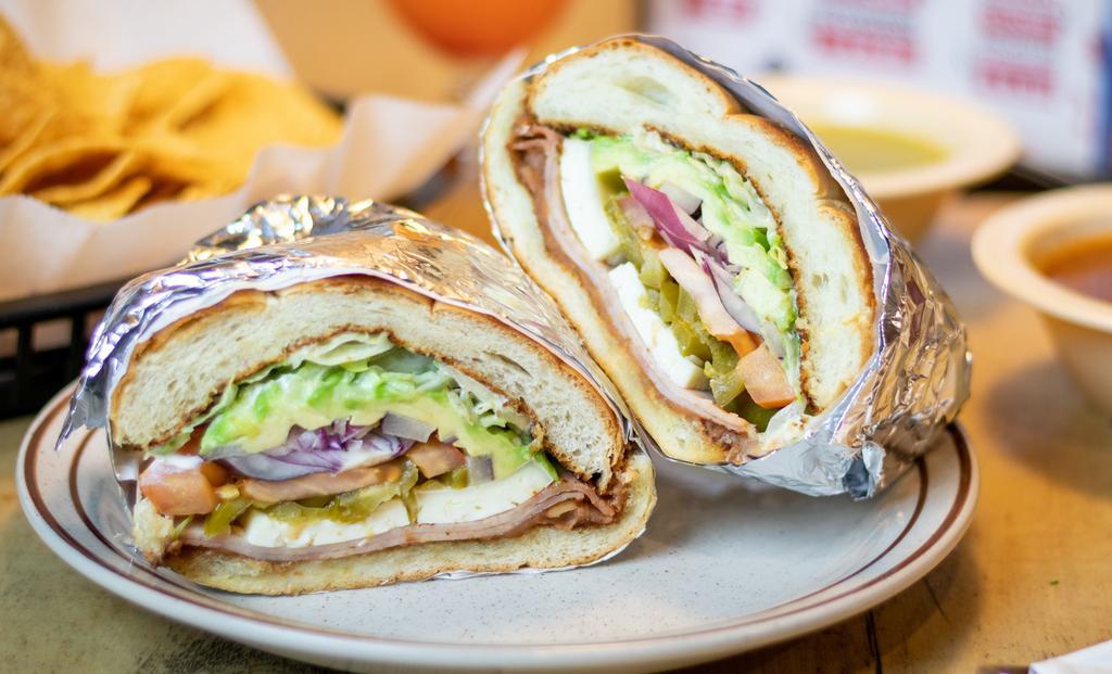 Torta Cubana  $10 · A Mexican sandwich with egg, ham, milanesa either chicken or beef, cheese, lettuce, tomatoes, red onions, jalapenos, sour cream, and slices of avocado