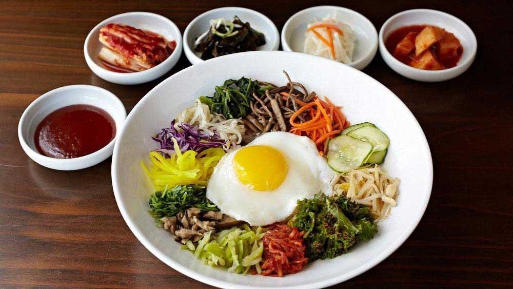 The Works Bibimbop · A bed of rice topped with spinach, mushroom, radish, julienned carrots, bean sprouts, quinoa, assorted vegetables, a fried egg, and your choice of protein.