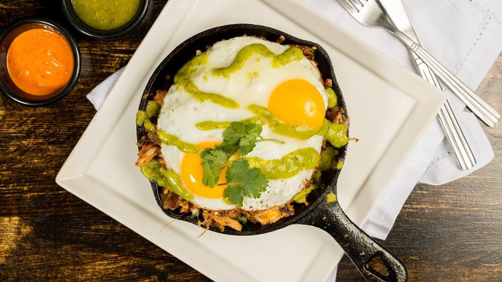 Carnitas Skillet · Tomato, onion, cilantro, jalapeno, bell peppers, cheddar and jack cheese, served over seasoned potatoes, topped w/ two eggs any style, topped with house avocado salsa.