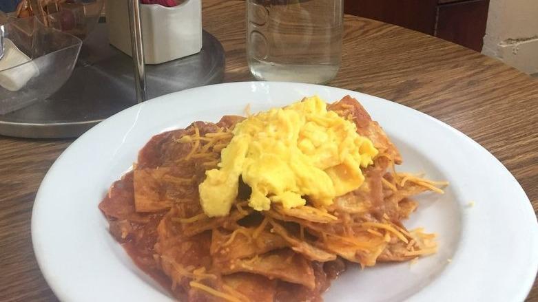 Chilaquiles · Homemade fried corn tortilla strips simmered in salsa rojo, covered with cheese and topped with refried beans and two scrambled eggs.