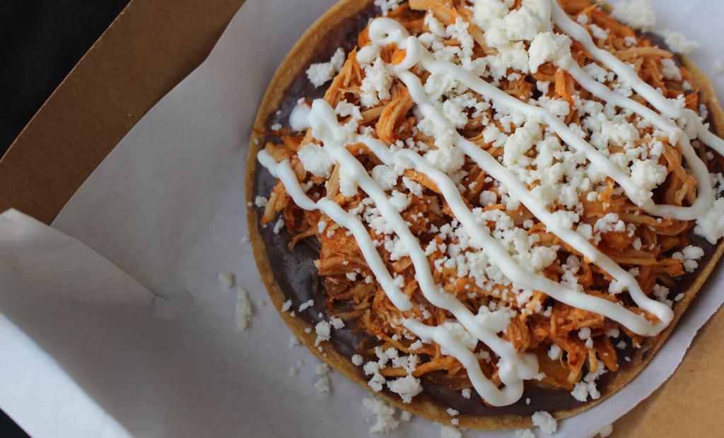 Tostada de Tinga · 1 crispy tostada with a layer of flavorful black beans, chicken tinga (shredded chicken in a chipotle tomato sauce) topped with quest fresco& sour cream.