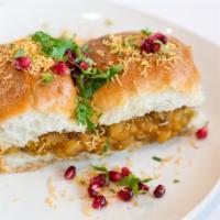 Dabeli · Potato mixture filled into a pav and topped with onion, pomegranate, cilantro, peanuts and s...