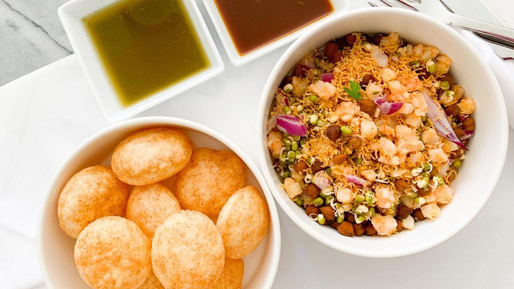Pani Poori · Crispy puffed wafers served with spicy mint water, chutneys, potatoes, sprouts and chickpeas.