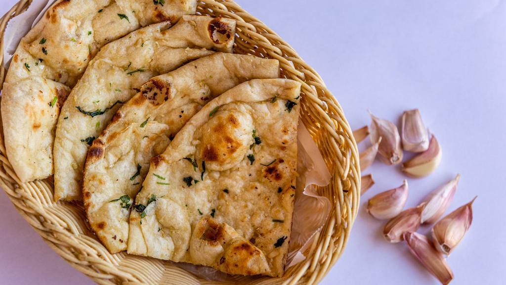 Garlic Naan · Clay oven leavened bread garnished with garlic and herbs.