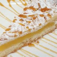 Torta Della Nonna · Pastry cream with a hint of lemon on a base of short pastry, topped with pine nuts, almond p...