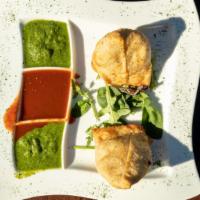 Samosas · Two golden-fried pastry puffs filled with potatoes and green peas.