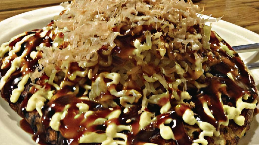 OKONOMIYAKI (Japanese Pancakes) · - Crispy outside Japanese pancake made with wheat flour, egg, seafood mix, fish cakes, veggies with topped of Okonomiyaki sauce, sesame seed, and fish flakes. Ramen noodle on top (Optional).