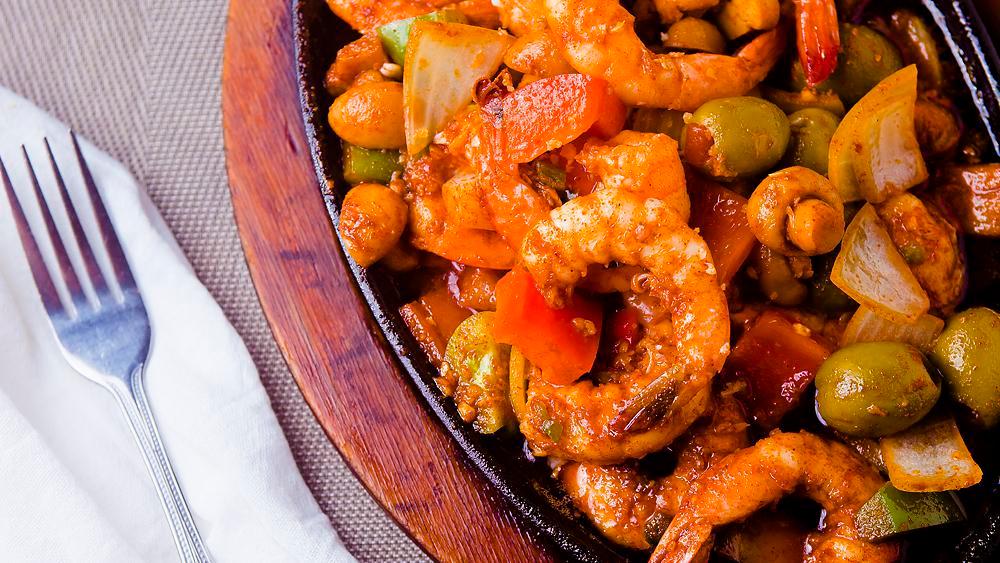 Gambas Al Ajillo · Shrimp, bell pepper sauteed in olive oil, garlic, paprika and served on a plate.