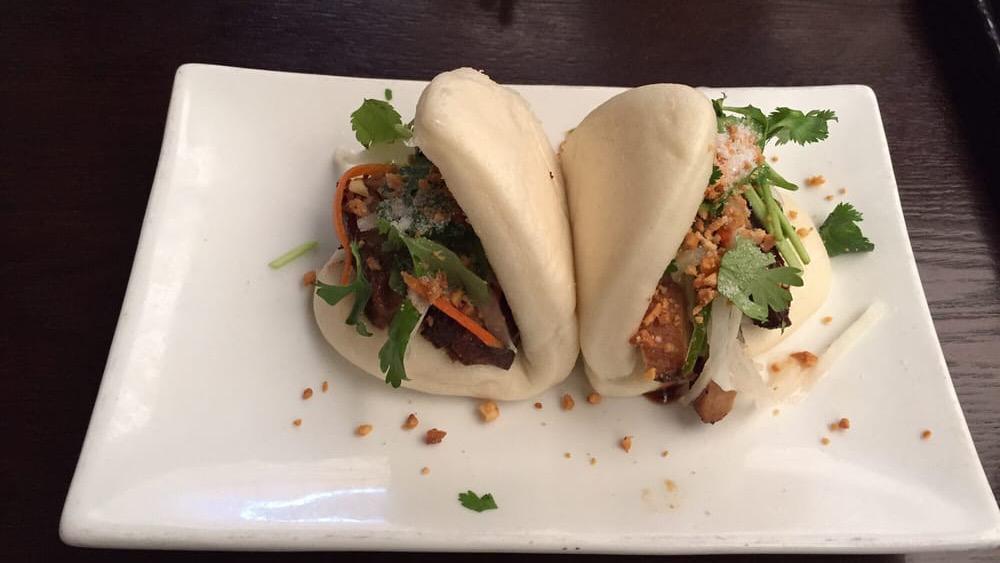 Pork Belly Bao (2) · Taiwanese style sliders made with braised pork belly, candied peanuts, pickled cucumber, cilantro stuffed in steamed lotus buns.