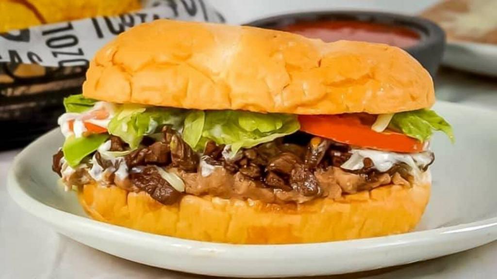 Torta Loca · Delicious Torta made with 3 types of meat (Carne Asada (Beef Steak), Al Pastor (BBQ Pork), Grilled Chicken, lettuce, tomatoes, jalapeños, sour cream, guacamole, cheese, and mayo.