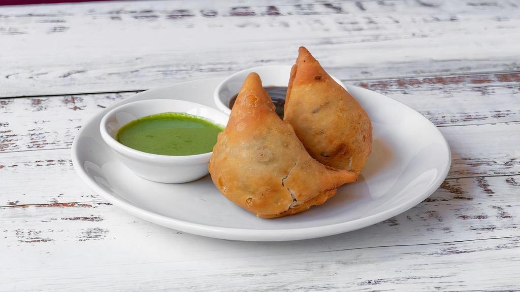 Samosas · A triangular fried pastry with a savory fillings, such as spiced potatoes, onions, and peas. Served with mint and tamarind chutney.