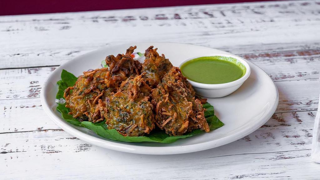 Vegetable Vajia (Pakoras) · Crispy fried vegetable fritters coated with chickpea flour. Consisting of carrots, cauliflower, onions, spinach, and cilantro, served with mint and tamarind chutney.