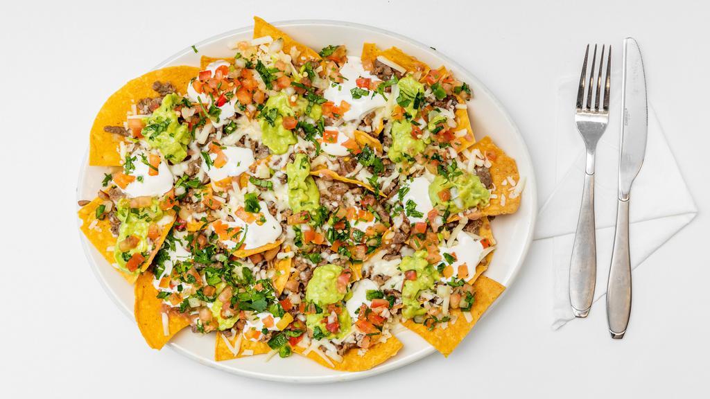 Super Nachos · Homemade crunchy tortilla chips served with a choice of meat, beans, cheese jalapenos, guacamole, sour cream & tomatoes.
