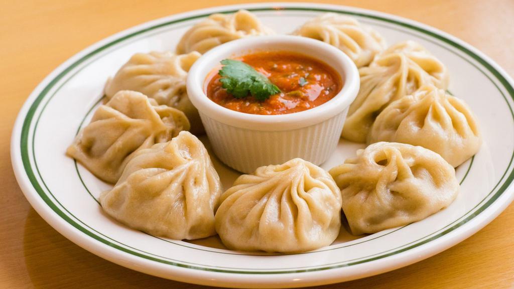 3. Chicken Momo (8 Pcs) · Steamed dumpling filled with minced chicken, onion garlic ginger paste, cilantro, nepali herb, and spices, served with tomato chutney.
