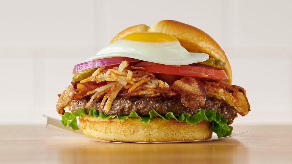 Hangover Burger · Crispy hash browns, Applewood-smoked bacon, lettuce, tomatoes, pickles, red onions, and mayo, with a sunny side-up egg* on top. Served with choice of side.