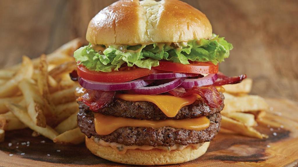 Bacon Double Cheddar Burger · Two juicy beef patties*, cooked to order, with Tillamook® cheddar, Applewood-smoked bacon, lettuce, red onion, tomato, pickles and Shari’s special sauce on a grilled split-top potato bun. Served with choice of side.