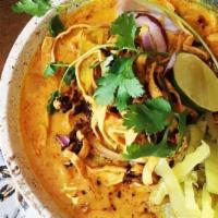Khao Soi · Chicken drumstick with Egg noodles in coconut curry. Lime, red onion, cilantro, and pickled ...