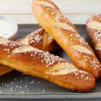 Warm Pretzels · 4 warm pretzels served with poblano queso dipping sauce garnished with green onions.