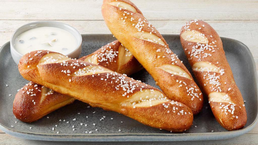 Warm Pretzels · 4 warm pretzels served with poblano queso dipping sauce garnished with green onions.