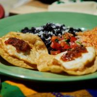 Huevos Rancheros · Two free range eggs over fried corn tort,. Serve with tomato rice, and refried beans.