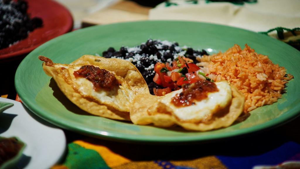Huevos Rancheros · Two free range eggs over fried corn tort,. Serve with tomato rice, and refried beans.