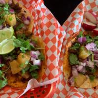 Tacos al Pastor & pineapple · Soft corn tortillas topped with al pastor and grilled pineapple, cilantro and red onions.