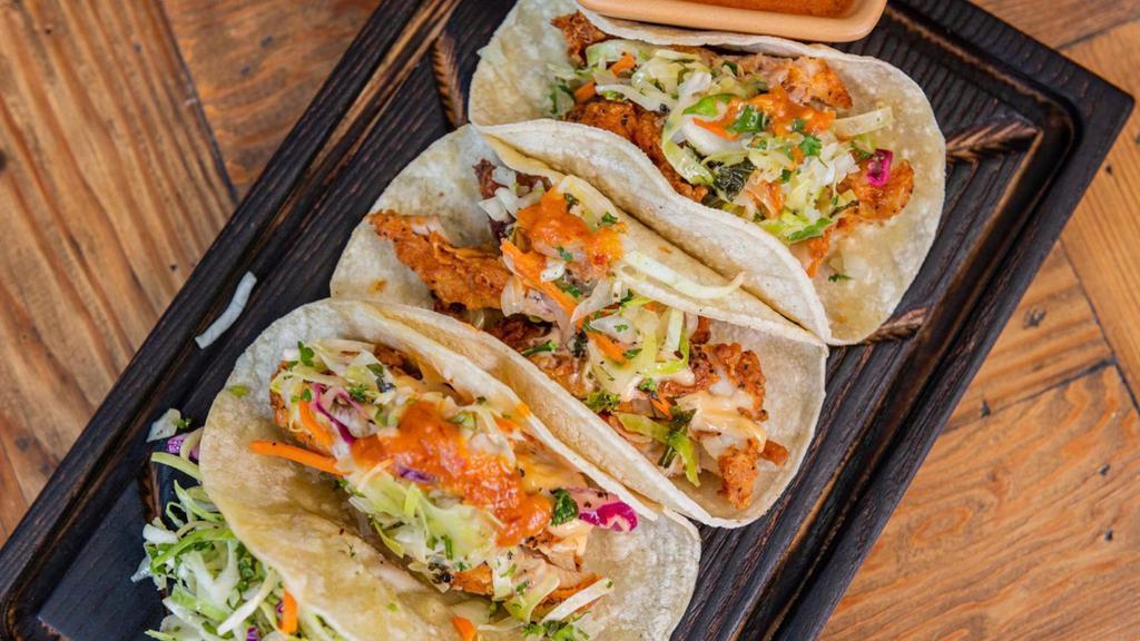 Fried Chicken Tacos Memphis Style · Three crispy tacos on flour tortillas with lemon cabbage slaw, Memphis sauce (spicy) garnished with onions and cilantro.