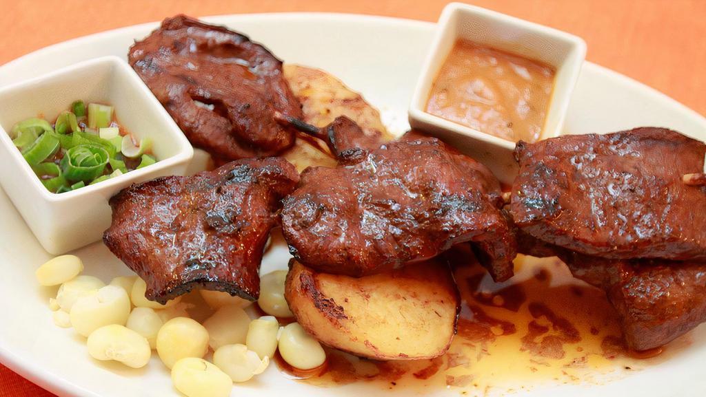 Anticuchos · Perfectly marinated beef heart pieces grilled in a special house marinade serve with Peruvian corn potato and Peruvian hot sauce (rocoto).