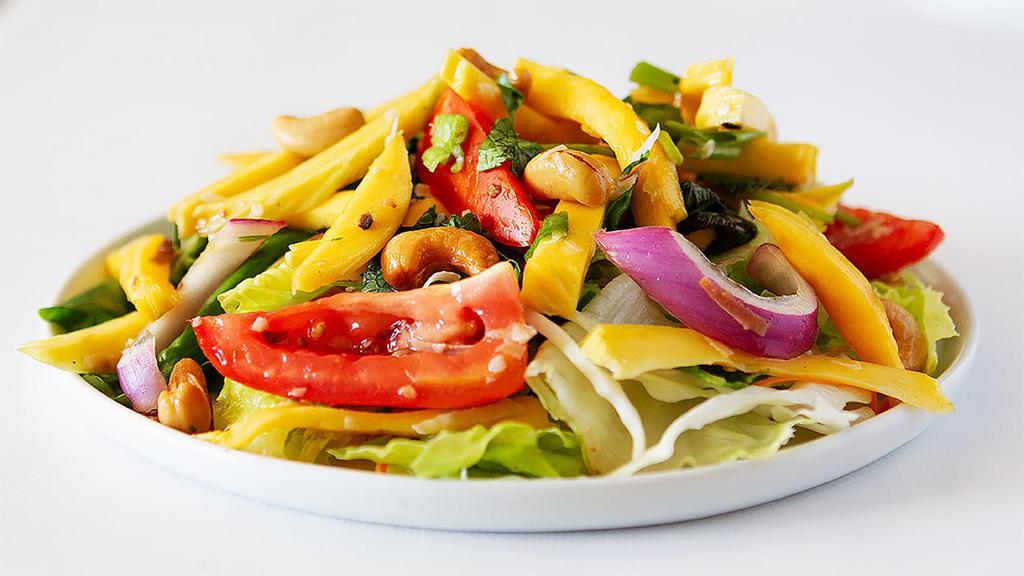 Mango Salad · Mango, red onion, roasted coconut, cashew nuts, and tomatoes in a Thai style dressing.