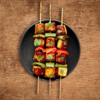 Charred Chicken Tikka · Boneless chunks of chicken marinated in herbs and spices barbecued in a clay oven on a skewer.