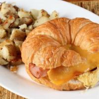 Croissant Sandwich · Two eggs scrambled, ham, cheddar cheese, lettuce, and tomatoes on a warm croissant.