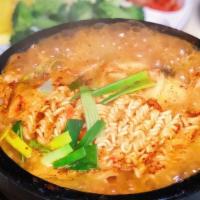 S-5. Budae Jjigae · Spicy stew with Kinchi, Spam, Hotdog, Rice cake, vegetables, and noodle in beef stock.