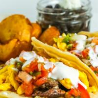 steak + eggs breakfast tacos** · Three corn tortillas loaded with grilled steak and scrambled eggs, topped with sour cream, p...