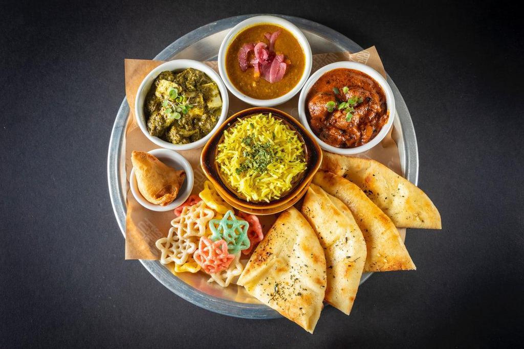The American Punjabi Thali · Saag Paneer, daal lentils, plus the choice of ghee makhni butter chicken or paneer,(Contains Cashews), turmeric rice, mini samosa, fryums, & kulcha naan. A nicely balanced feast served in bowls with your choice of rice and bread, pickles, pico kachumber & papadum. Egg washed housemade flatbread, onions, cilantro chutney, choice of protein, side of housemade potato crisps and pico. In the Bay Area, Thalis will be served with Fryums + Mini Samosa.  Outside the Bay Area, Kathis will be served with Pico + Pickles