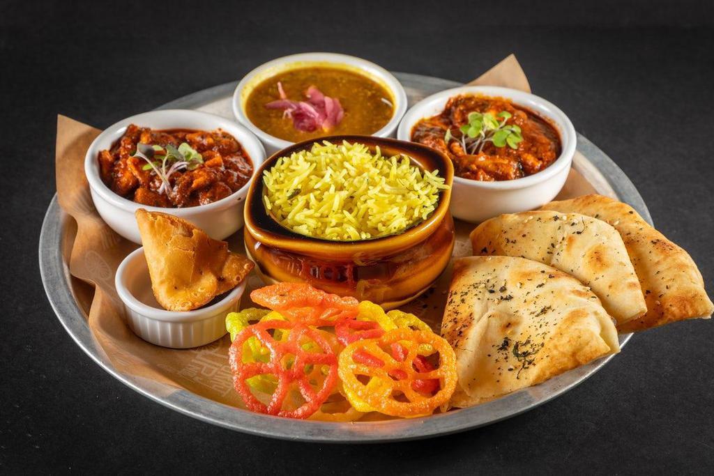 Death By Tikka Masala Thali · chicken tikka masala, paneer tikka masala or a combo of chicken and paneer, daal lentils, turmeric rice, mini samosa, fryums, & kulcha naan. A nicely balanced feast served in bowls with your choice of rice and bread, pickles, pico kachumber & papadum. Egg washed housemade flatbread, onions, cilantro chutney, choice of protein, side of housemade potato crisps and pico. In the Bay Area, Thalis will be served with Fryums + Mini Samosa.  Outside the Bay Area, Kathis will be served with Pico + Pickles