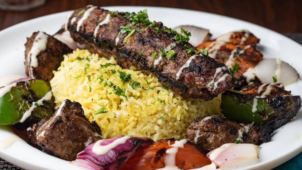 Kefta Kabob Plate · Kefta kabob served with a side of rice, hummus, Greek salad, and fresh pita bread along with grilled onions and tomatoes on top of the meat.